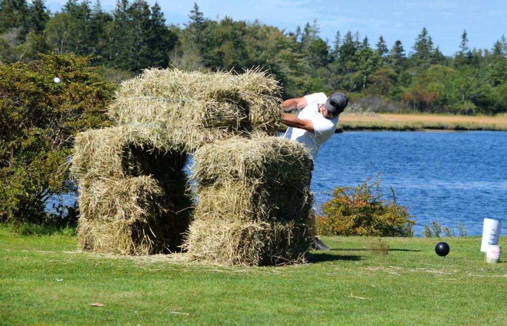 Teeing off through bales of hay was just the first obstacle on #1 at the River Hills Golf and Country Club in Clyde River during the first-ever Superintendent Revenge Scramble. - Kathy Johnson