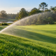 Irrigation watering a sloped golf course near a putting green.